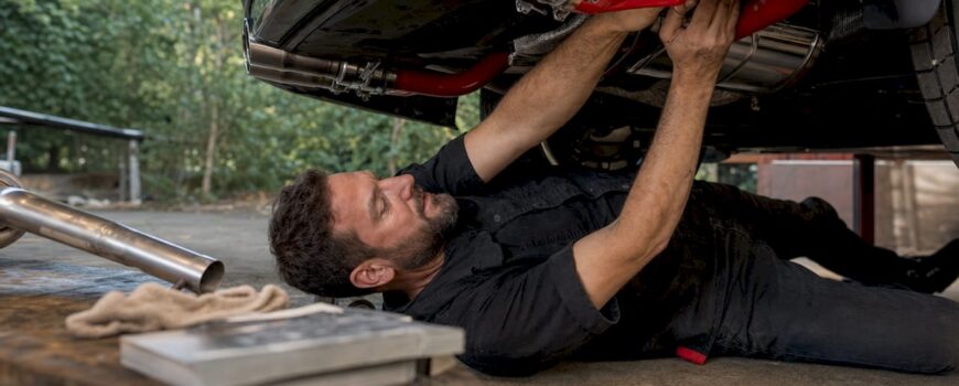 Man installing BMW exhaust in garage workshop