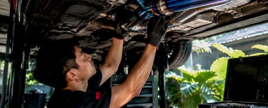 Mechanic installing titanium exhaust on car