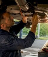 Technician adjusting active exhaust valve in workshop