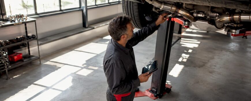 Technician inspecting exhaust system on dyno lift