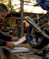 Man reviewing motorcycle exhaust certification in garage