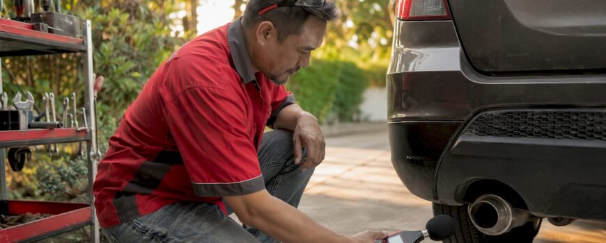 Technician measuring car exhaust noise outdoors