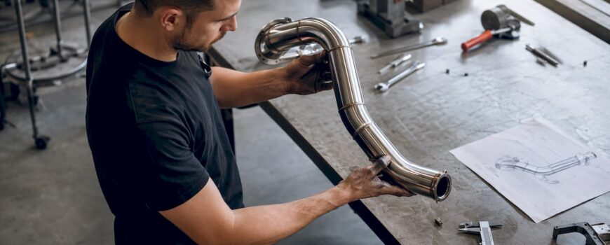 Mechanic inspecting mandrel-bent exhaust pipe