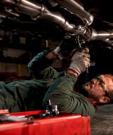 Technician installing full exhaust system under car