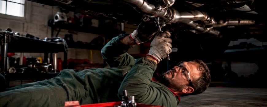 Technician installing full exhaust system under car