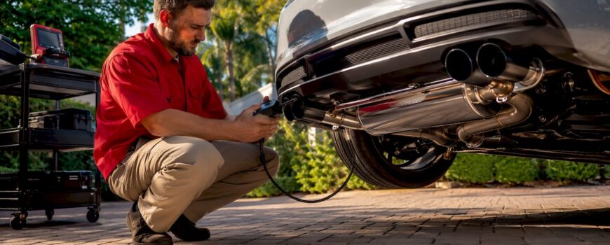 Technician inspecting valved exhaust system in garage