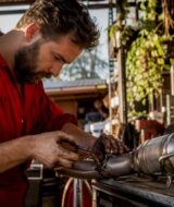 Technician fitting custom exhaust under car