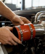 Hands fitting silicone turbo hose in engine bay