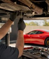 Hands inspecting exhaust system underside