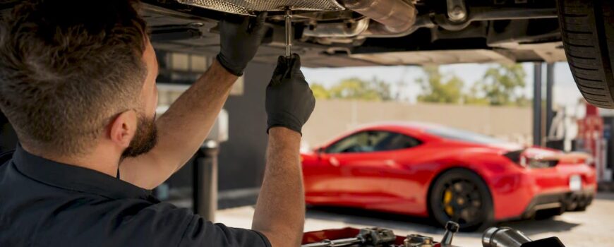 Hands inspecting exhaust system underside