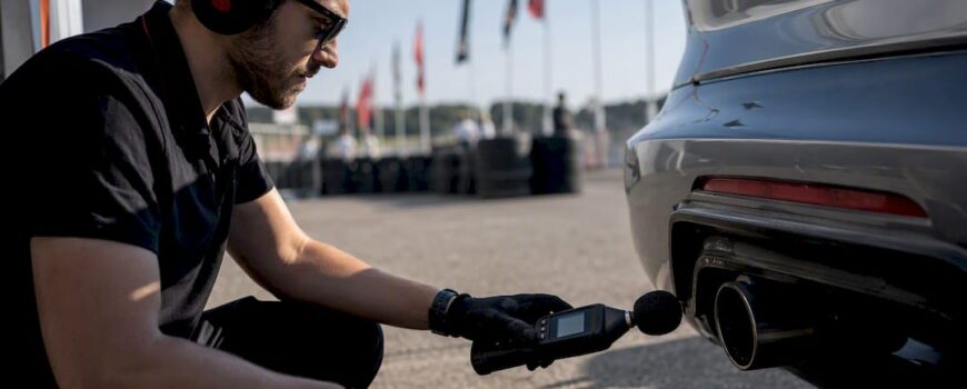 Technician measuring exhaust noise with handheld meter