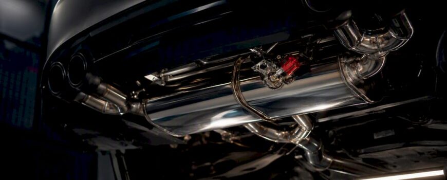 Valved exhaust hardware beneath performance coupe