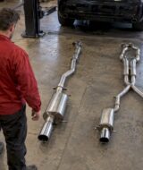 Technician comparing single and dual exhaust layouts