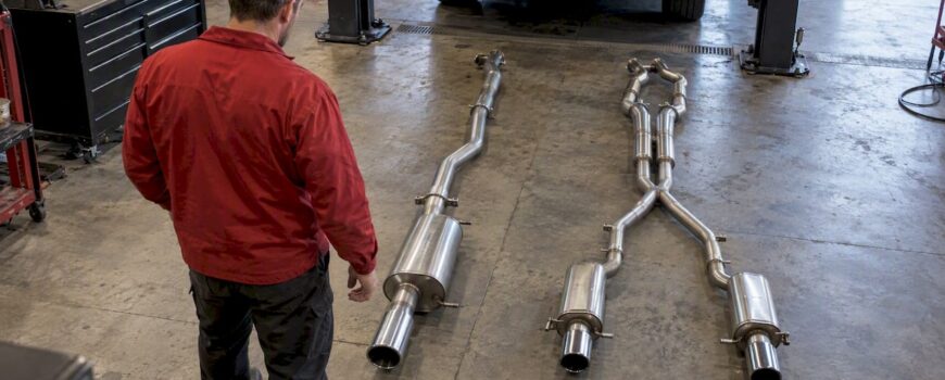 Technician comparing single and dual exhaust layouts