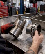 Mechanic comparing welded and V-band exhaust joints