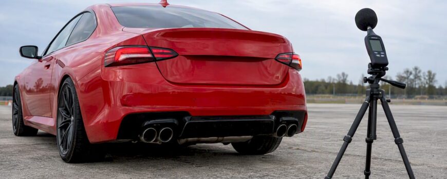 Red performance coupe beside exhaust sound meter